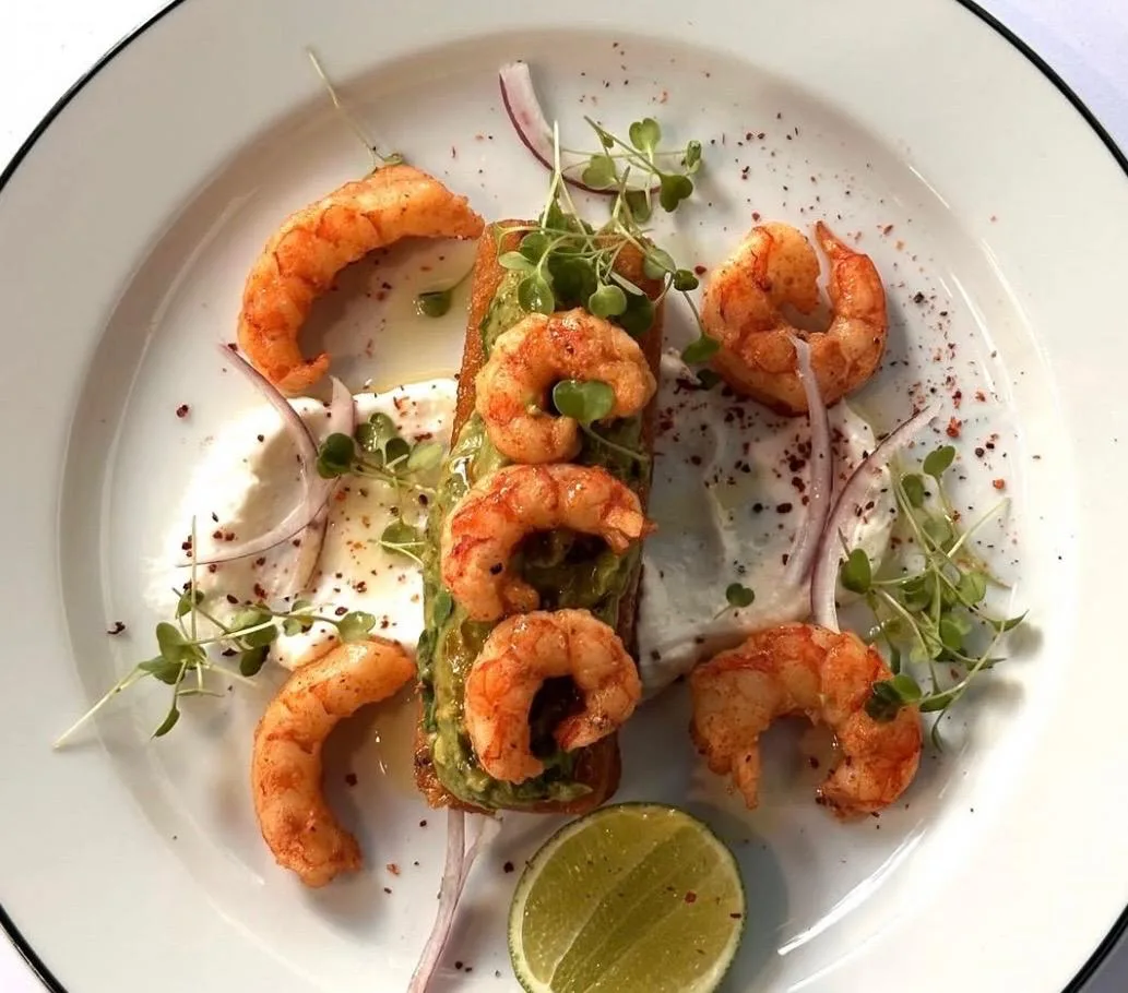 Langostinos salteados sobre tostada de palta con microgreens